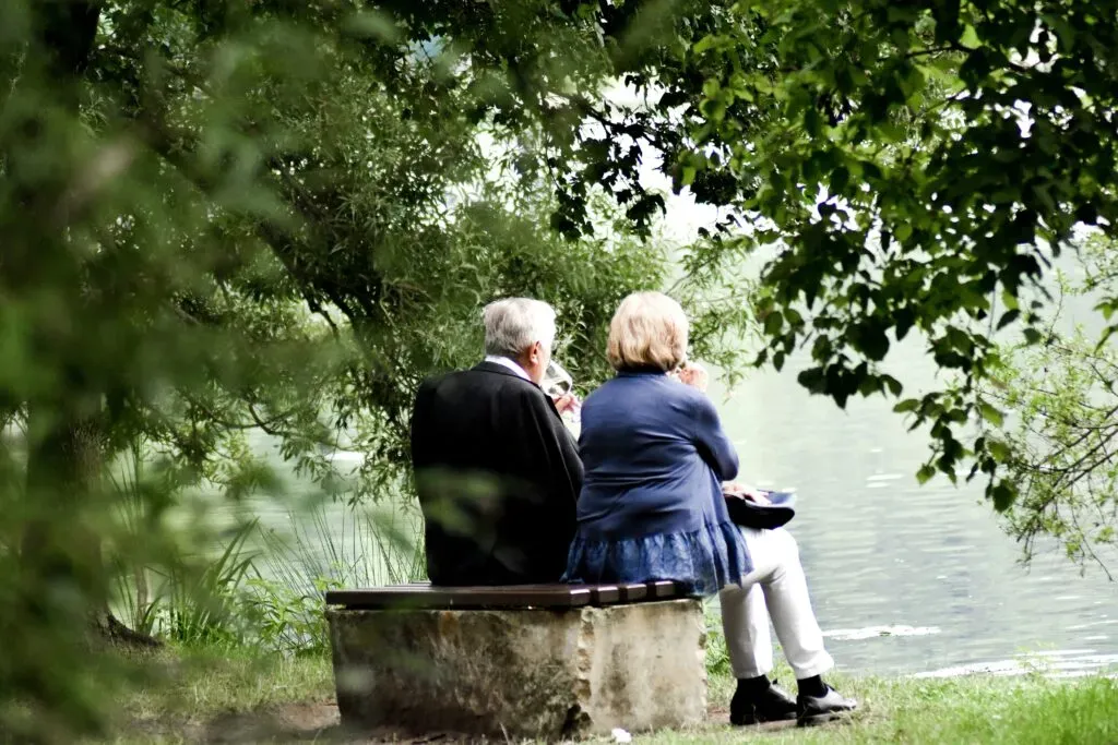 Couple sénior assis sur un banc au bord de l'eau